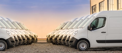 Sixteen delivery vans parked together that need commercial auto insurance