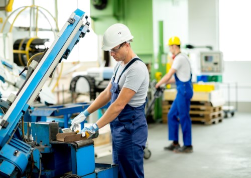 Factory worker cutting metal at a workstation